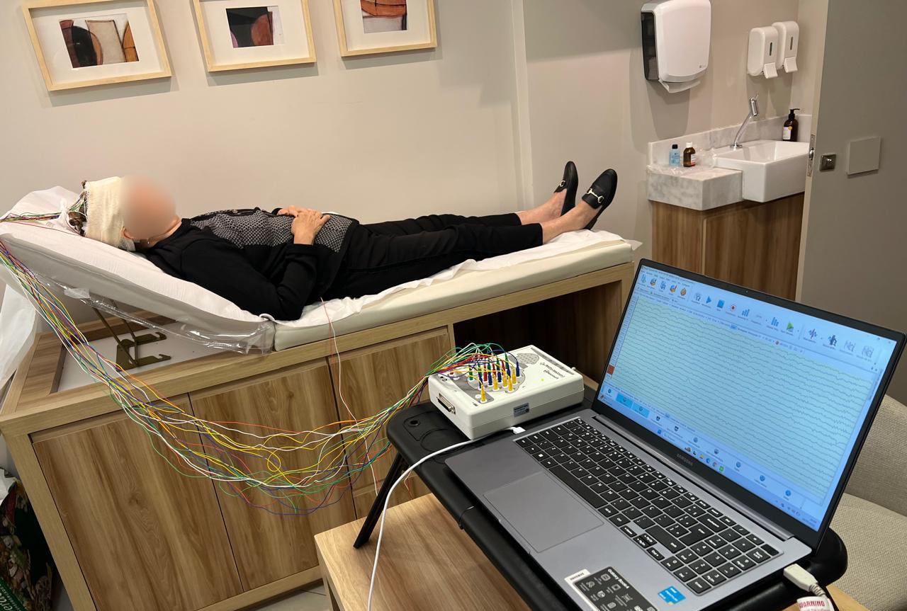 Paciente realizando EEG de rotina na clínica Alpha Pulse, com eletrodos conectados ao equipamento de neurofisiologia